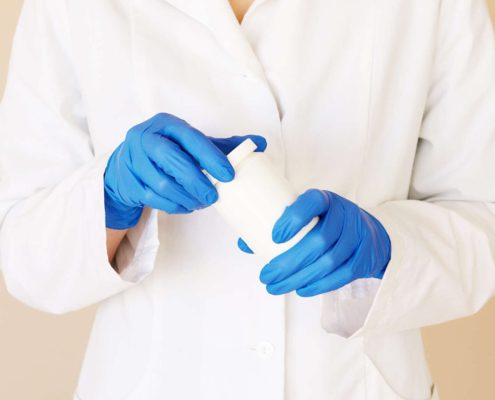 Lab technician in gloves handling a sample container for food or water testing