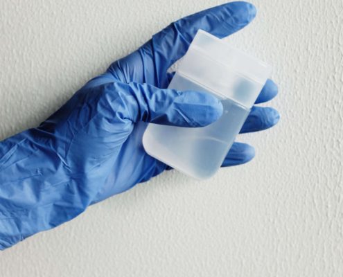Gloved technician holding a water sample container for certified well testing collection