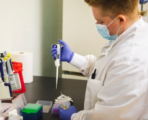 Lab technician using a pipette to prepare samples for water or food safety testing